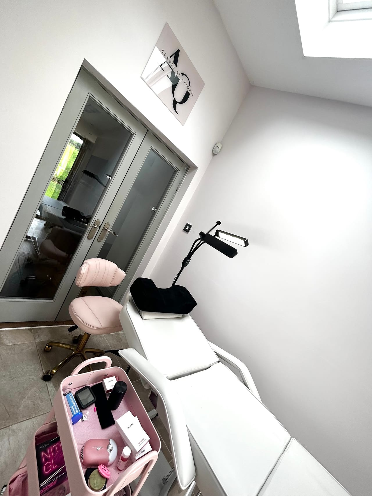 Beauty By Abigail's treatment room with the real AQ wall sign and pale pink furnishings